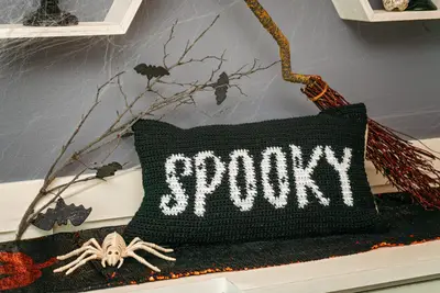 Spooky Crochet Pillow Cover with a skeleton spider, bats and a witch's broom