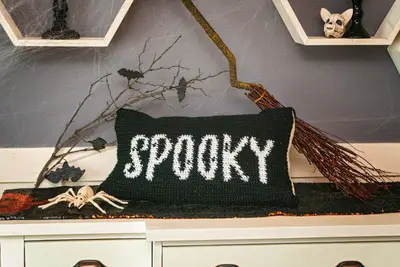 Black Spooky Crochet Pillow Cover on a white dresser with Halloween decor