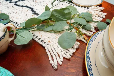 Close up of the Thankful runner's twisted fringe with eucalyptus and teacups