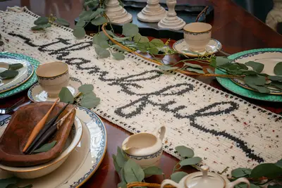 Thankful Crochet Table Runner in black and oatmeal on a dining table with china