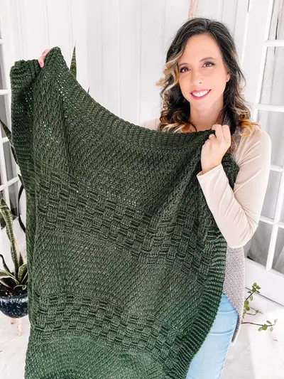 Woman showing the texture of the green Totally Textured Crochet Blanket