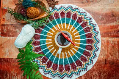 Traveler Fair Isle yoke laid flat on wood with yarn and a crochet hook