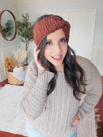 Woman wearing a rust Twisted Wheat Ear Warmer and an oatmeal sweater
