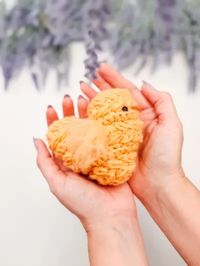 Hands holding a fluffy yellow Wheat Stitch Chick