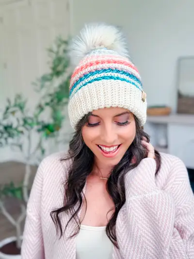 Woman wearing a cream Wheat Stitch Crochet Beanie with bright stripes and a pom pom