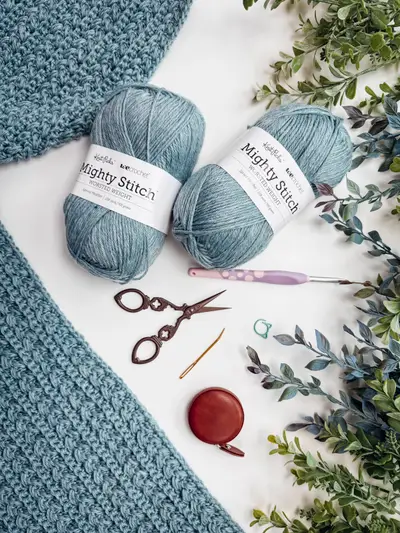 Blue Wheat Stitch Crochet Cardigan in progress with skeins of yarn and scissors
