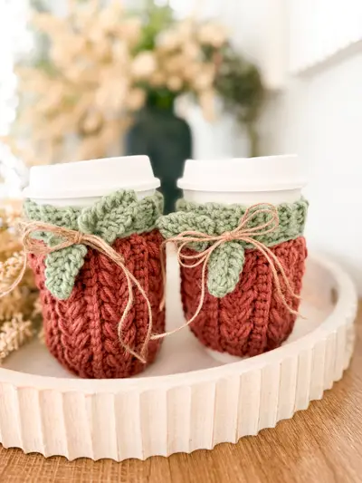 Two coffee cups wearing rust Wheat Stitch Pumpkin Cozies