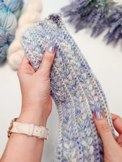 Hands holding a lavender Wheat Stitch Ear Warmer