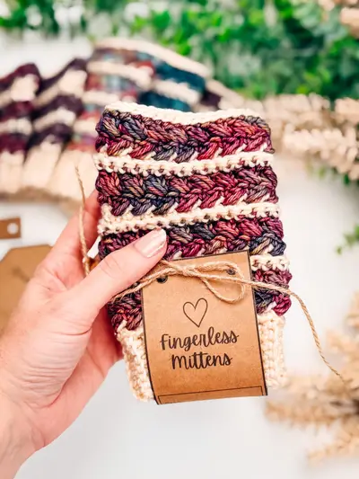 Hand holding a Wheat Stitch Fingerless Mitten on a kraft gift card