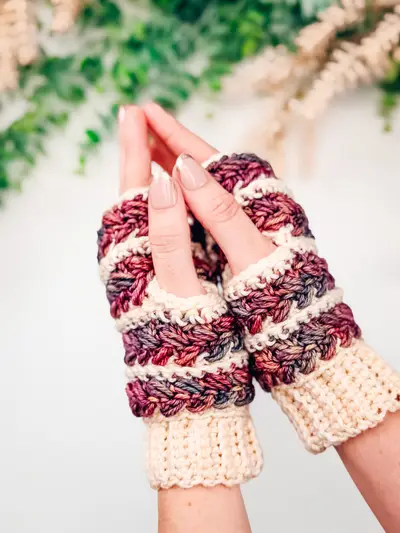 Hands wearing Wheat Stitch Fingerless Mittens in burgundy and cream stripes