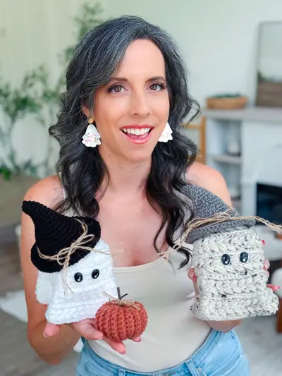 Woman holding two Wheat Stitch Ghosts and a crochet pumpkin
