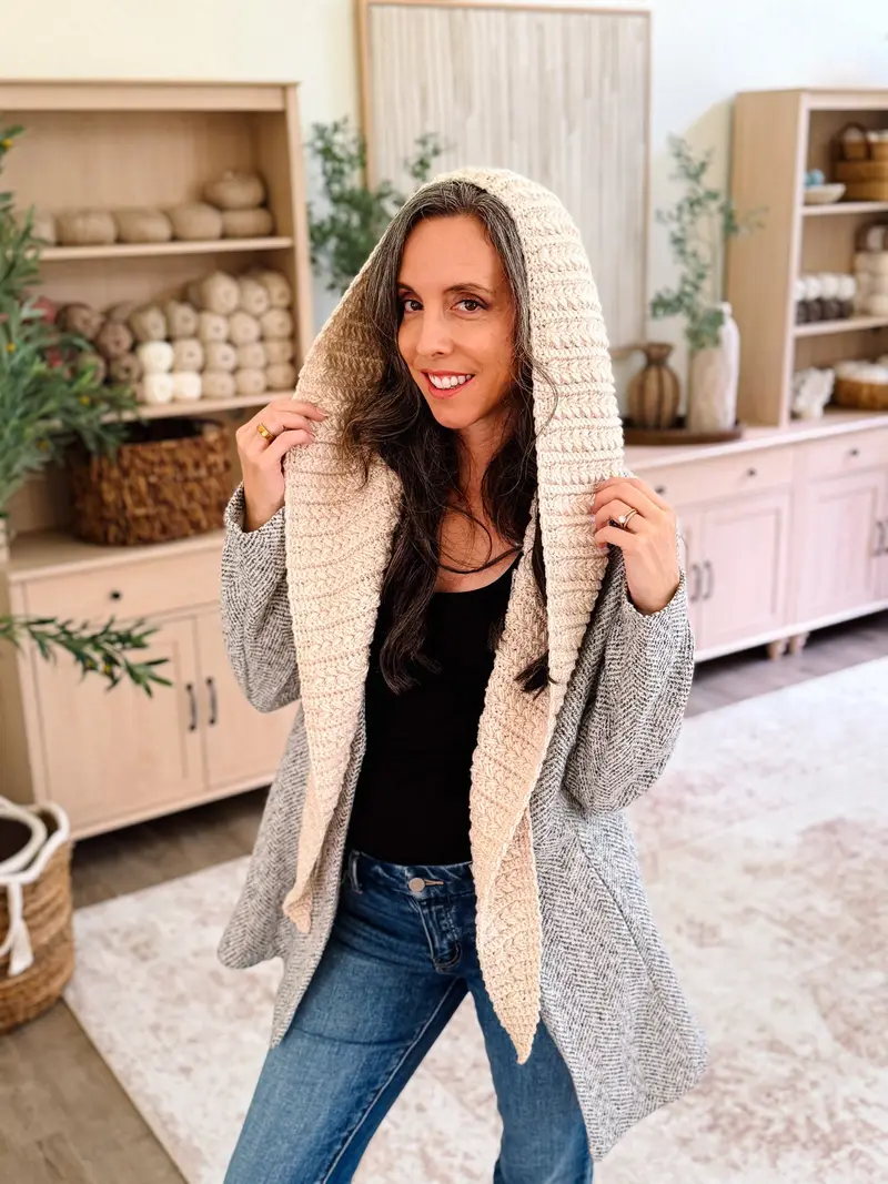 Woman wearing the cream Wheat Stitch Hooded Scarf with a gray coat