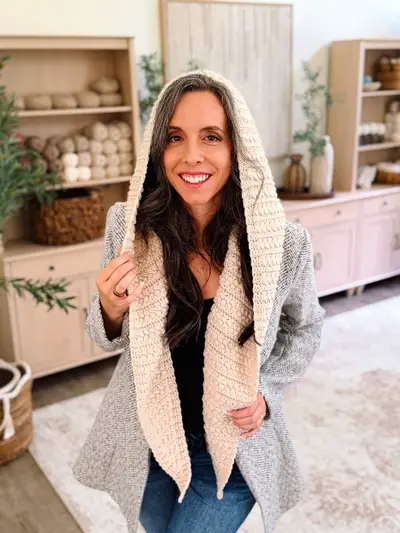 Smiling woman with the hood of the cream Wheat Stitch Hooded Scarf up