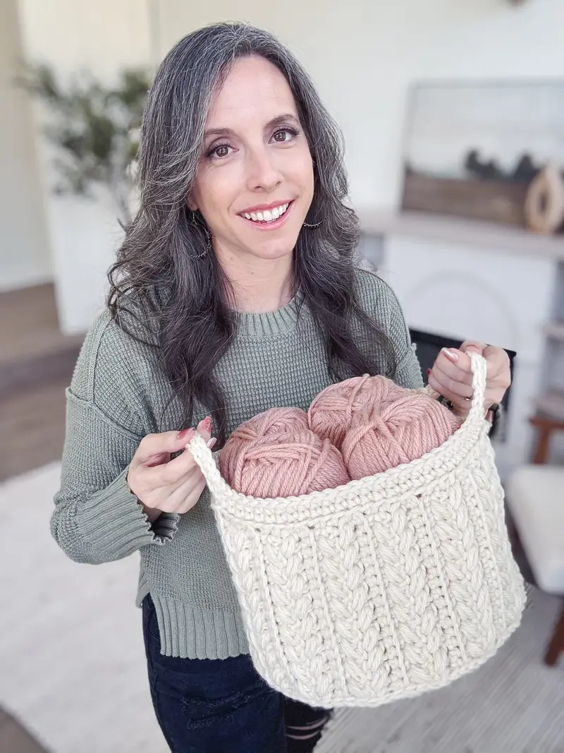 Woman holding a cream Wheat Stitch Nesting Basket filled with pink yarn