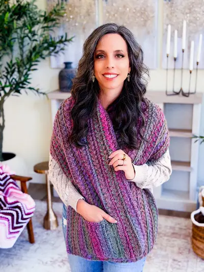 Woman wearing the Wheat Stitch Pocket Shawl in purple and teal variegated yarn