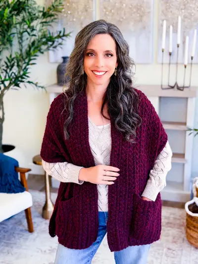 Woman wearing a burgundy Wheat Stitch Pocket Shawl with a hand in a pocket