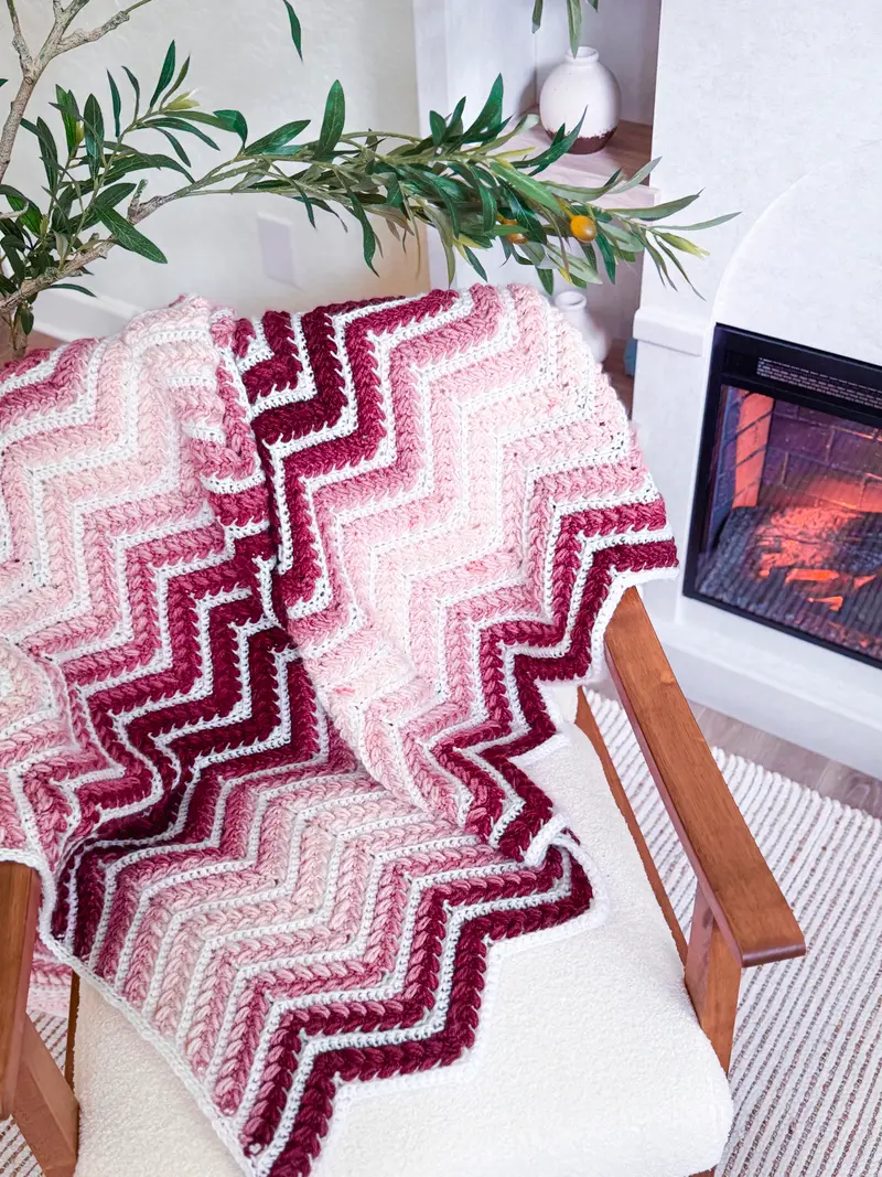 Wheat Stitch Ripple Blanket in burgundy, pink and white chevrons on a chair