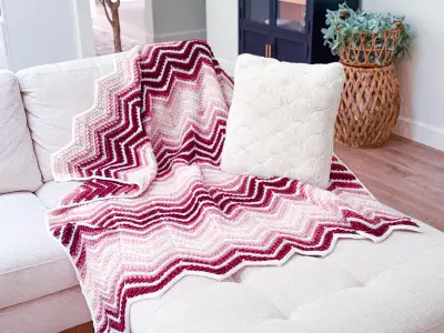 Wheat Stitch Ripple Blanket draped over a white bench
