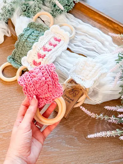 Hand holding a pink Wheat Stitch Scalloped Dishtowel Holder with a wooden ring