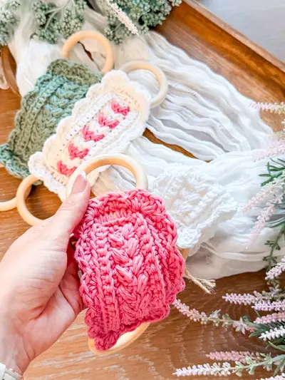 Hand holding a coral Wheat Stitch Scalloped Dishtowel Holder