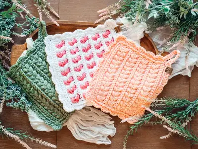 Wheat Stitch Scalloped Hotpads in sage, pink and peach on a wooden board