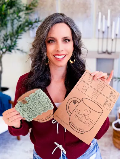 Woman holding a sage mug cozy and a printed gift card