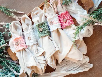 Row of rolled napkins with pink, white and sage scalloped napkin rings