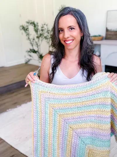 Woman holding up a pastel Wheat Stitch Triangle Shawl