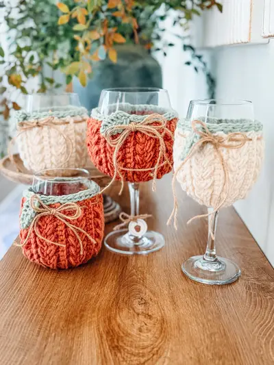 Wheat Stitch Wine Glass Cozies in orange, cream and sage on wine glasses