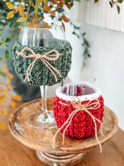Wheat Stitch Wine Glass Cozies in green and red with twine bows on a stand