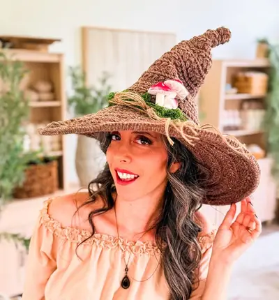 Woman wearing a brown Wheat Stitch Witch Hat with a wide brim and mushroom trim