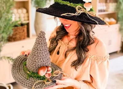 Woman holding a small Wheat Stitch Witch Hat while wearing a black one
