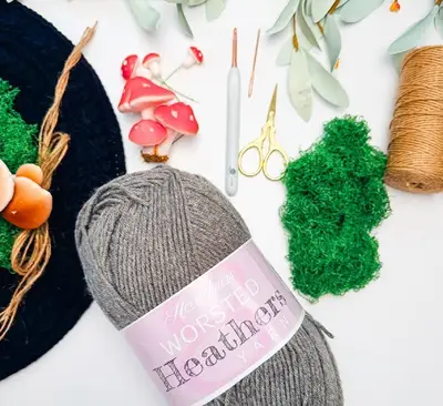 Supplies for the Wheat Stitch Witch Hat with gray yarn, twine, moss and mushrooms