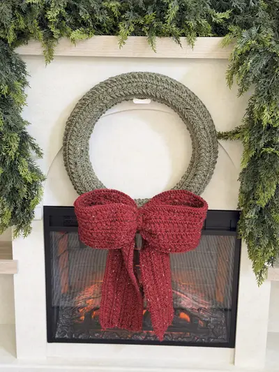 Sage Wheat Stitch Wreath with a burgundy bow over a fireplace