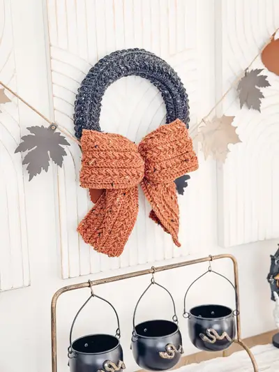 Black Wheat Stitch Wreath with a rust bow above a Halloween display