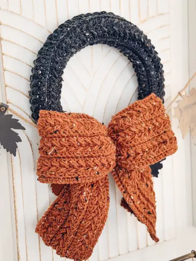 Close up of a black Wheat Stitch Wreath with a speckled rust bow