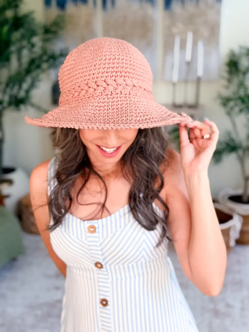 Woman wearing a pink Wheatfield Sun Hat with a wide floppy brim
