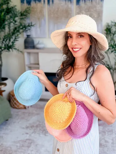 Woman in a cream Wheatfield Sun Hat holding blue, yellow and pink ones