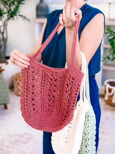 Hand holding a rust Willow Mesh Market Bag