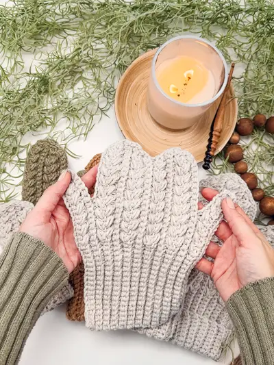 Hands holding a cream Winter Wheat Flat Crochet Mitten to show the texture