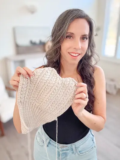 Woman holding up a cream Winter Wheat Flat Crochet Mitten