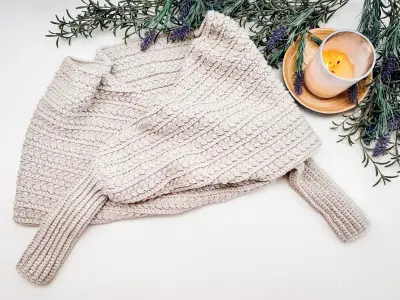 Cream Winter Wheat Sweater Scarf laid flat with greenery and a candle