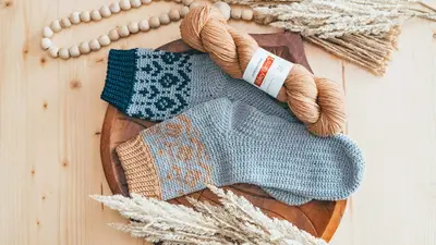 Woodland Walker Crochet Socks laid on a wooden tray with a skein of yarn